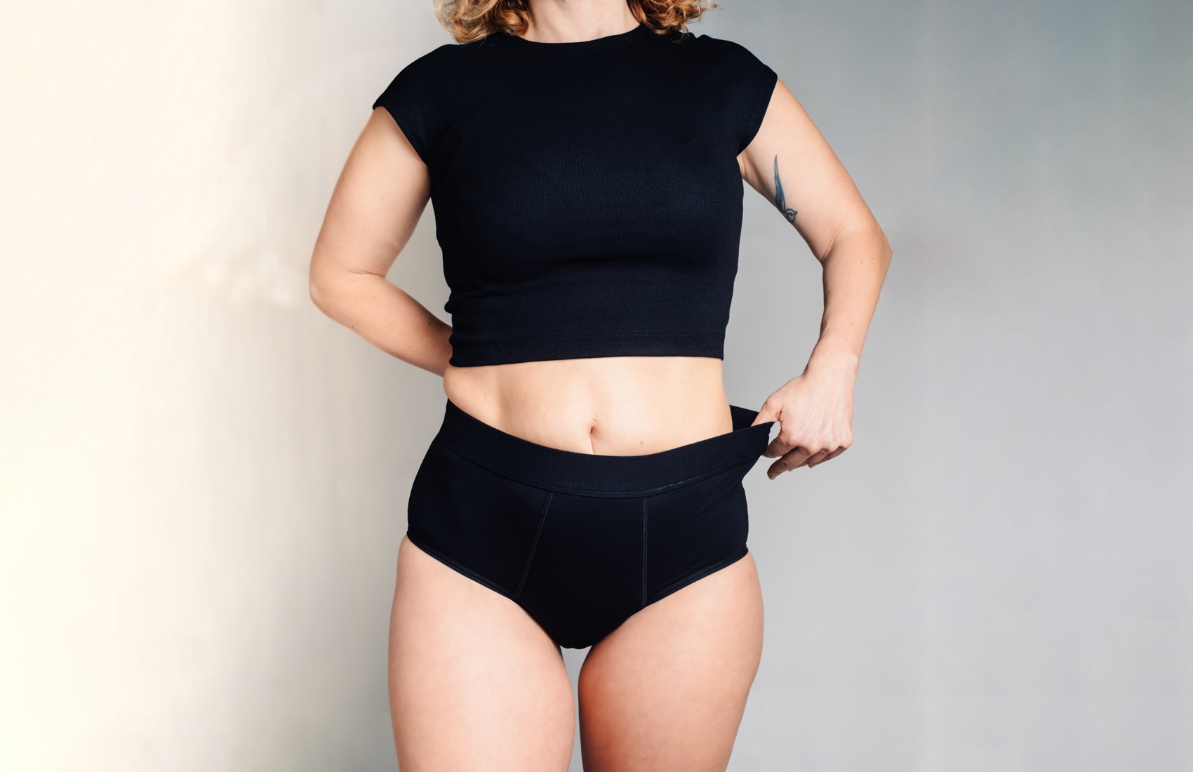 L'Indispensable portée de face. La culotte menstruelle noire, large élastique à la taille, confortable pour flux très abondant et retour de couche.