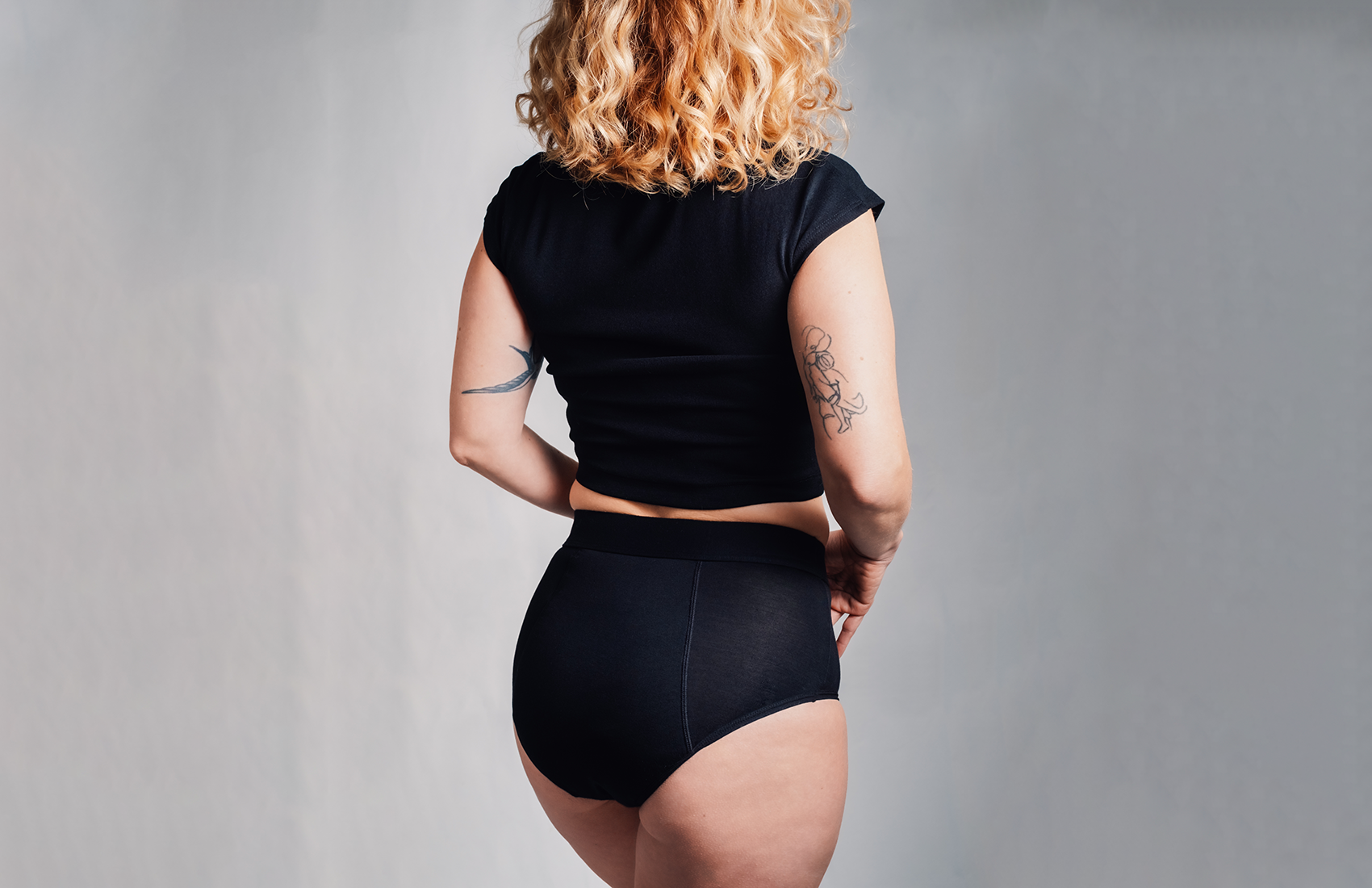 L'Indispensable portée de dos. La culotte menstruelle noire, confortable pour flux très abondant et retour de couche